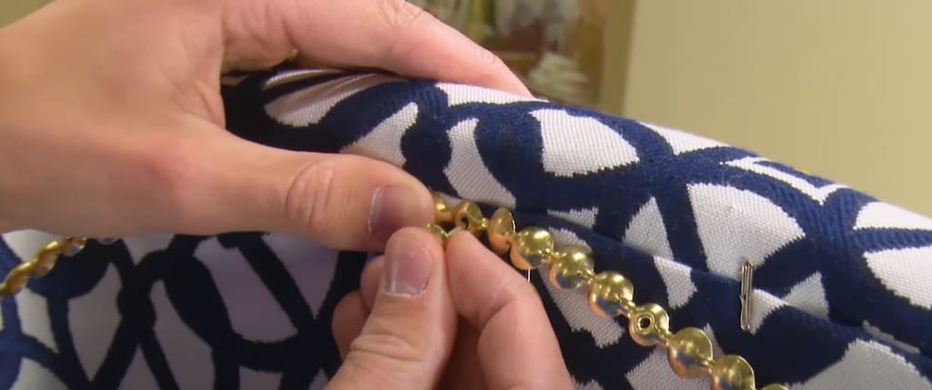 A person attaching the nail trim to the cushion upholstery