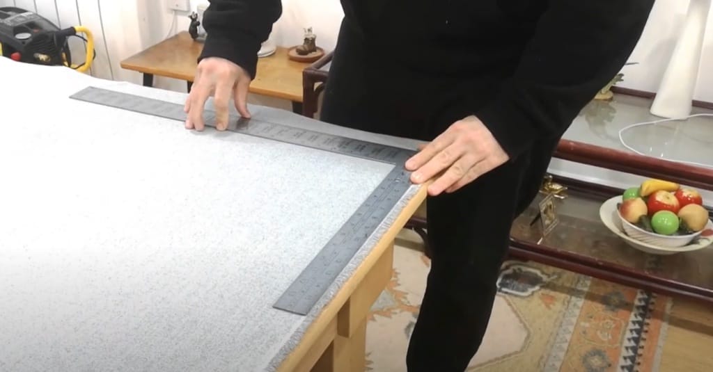 A person measuring the fabric on the table