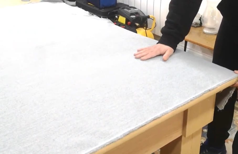 A person touching the laid fabric on the table