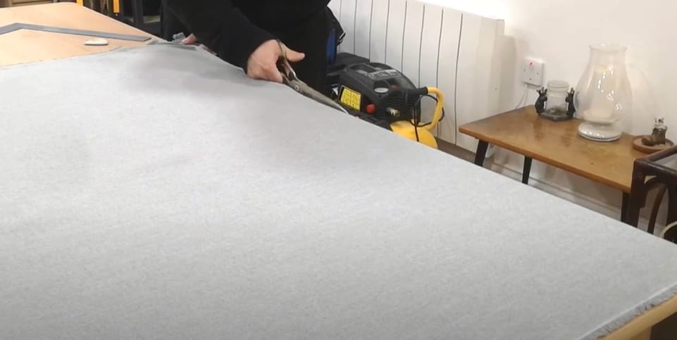 A person using fabric scissor to cut the fabric on the table