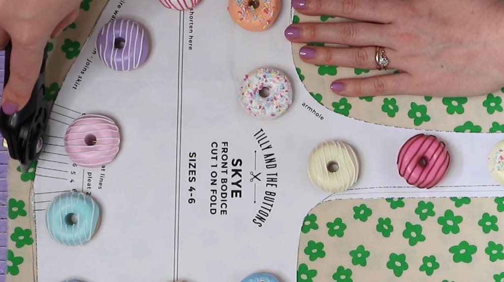 A woman cutting the fabrics with doughnut design buttons in it