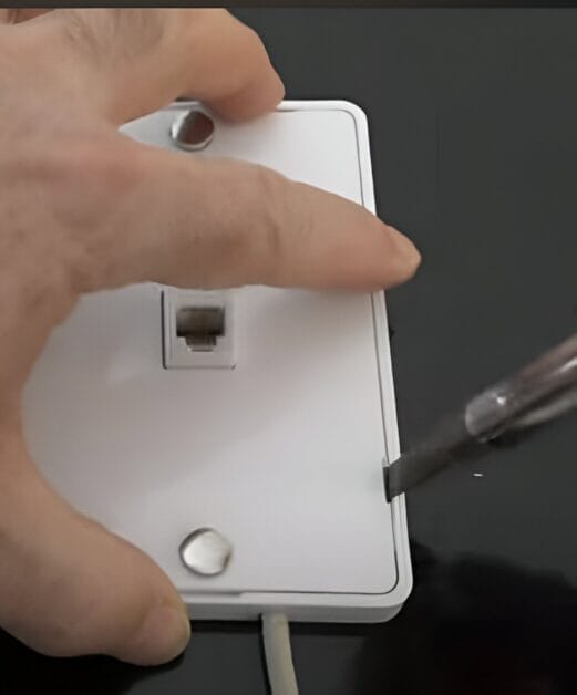 A person mounting a phone jack plate