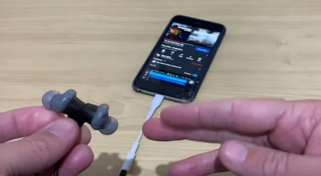 A person is test the headphones that is connected to a phone