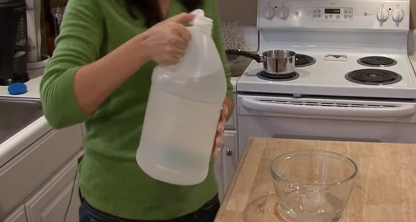 a woman holding a bottle of mixture and pouring it into a bowl