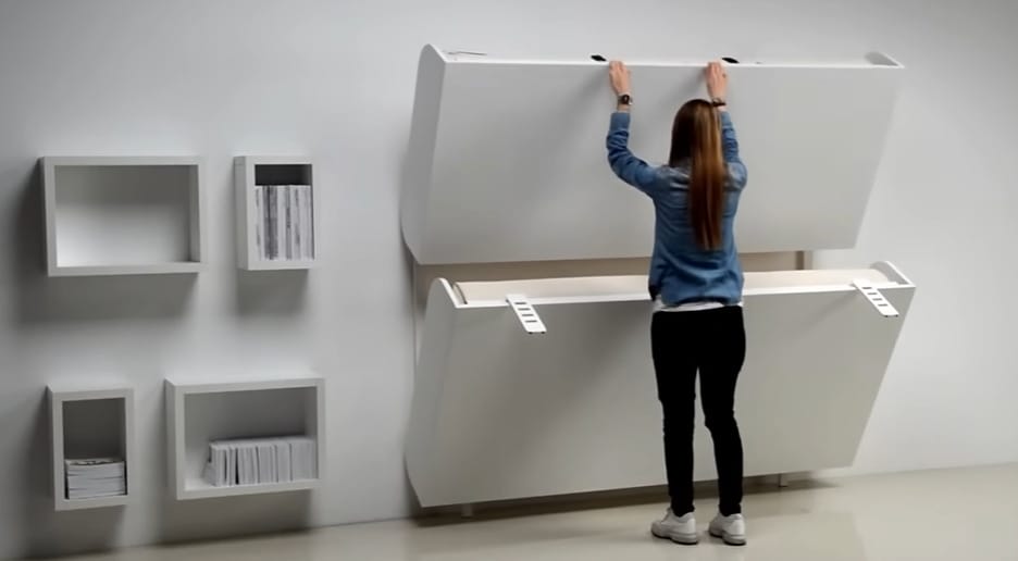 A woman showing the hidden storage space in a room