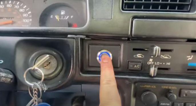 A person is pressing a button on a car dashboard