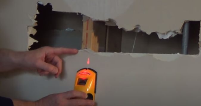 A person marking the area where the stud finder beeps