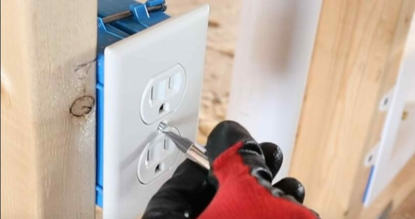 A person attaching the faceplate of an outlet using a screw