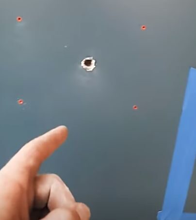 A person pointing at the hole on the wall