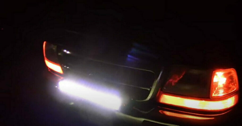 A car with a light bar on its rear bumper at night.