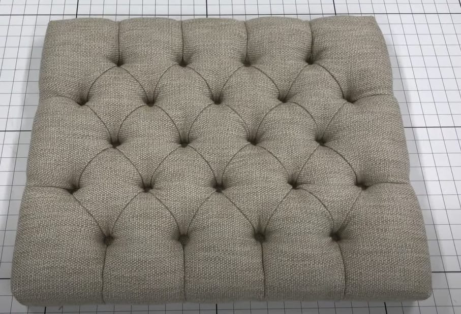 A tufted cushion with beige fabric