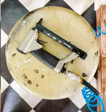 A nail gun sits on top of a checkered table