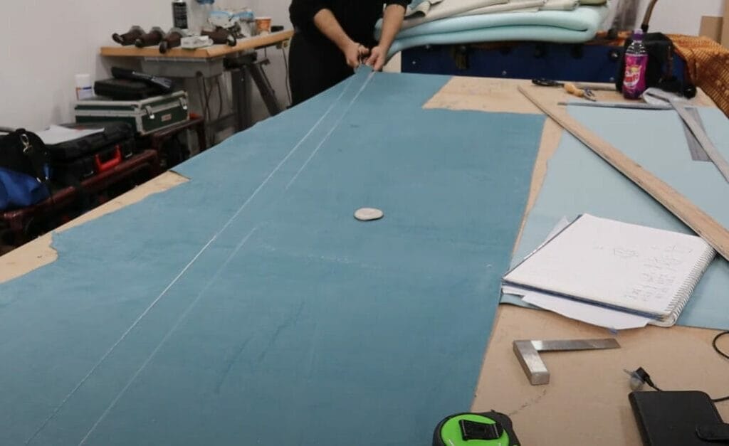 A person is cutting a leather clothe on a table