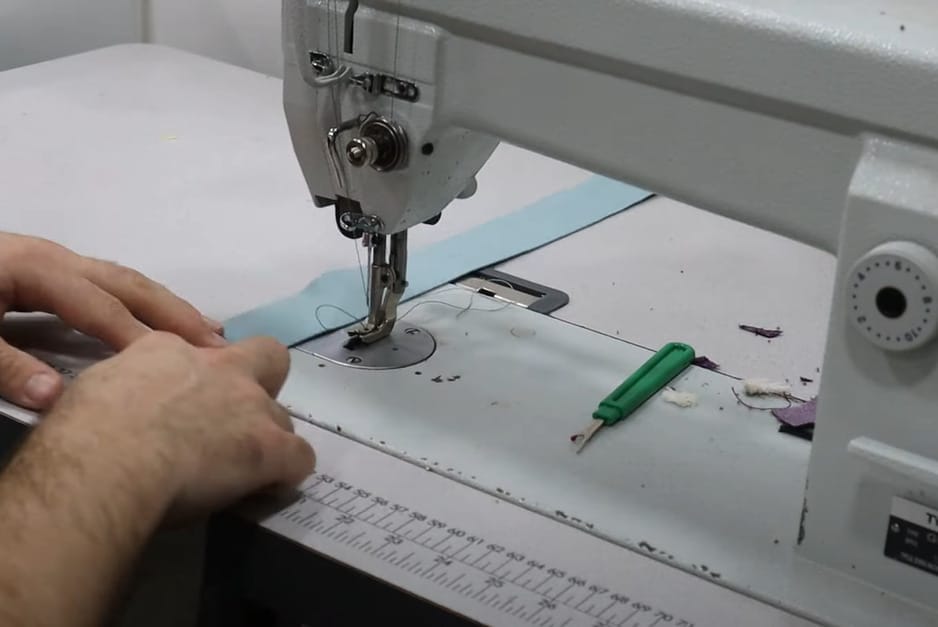 A person using a sewing machine to sew upholstery fabric