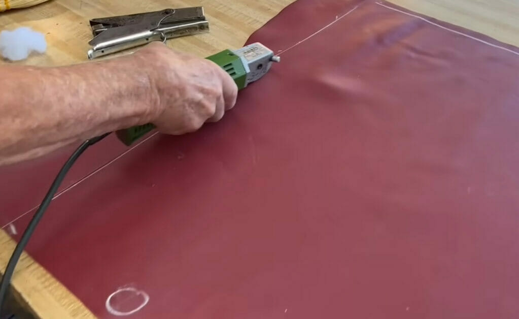 A man using a tool to cut leather for upholstery