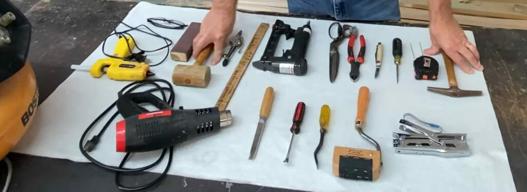 A man is holding a variety of tools and materials on a table