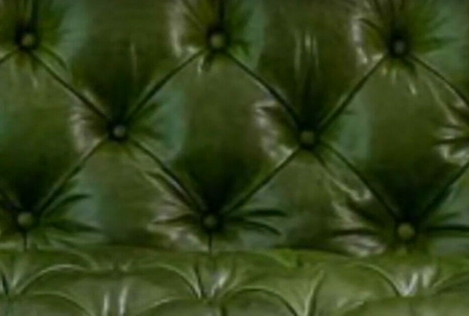 A close up of a green leather couch showcasing the diamond tufting in upholstery