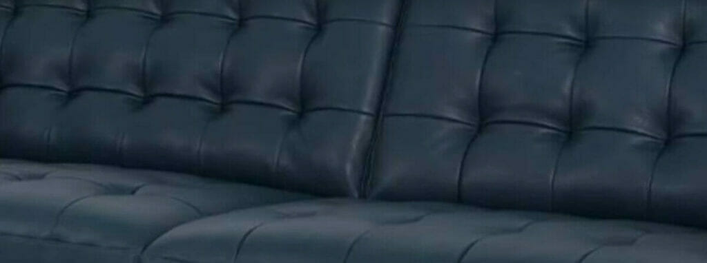 A close up of a blue leather sofa showcasing masterful biscuit tufting in upholstery