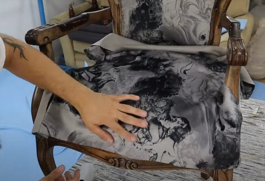 A person putting fabric with design on the upholstered chair