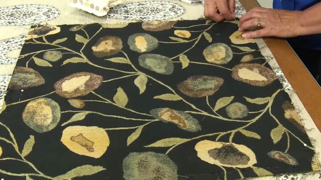 A person is cutting out a new fabric for a cushion upholstery