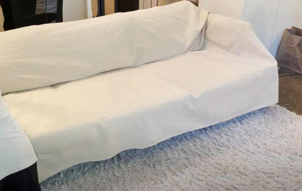 A white couch with a white drape cover in it