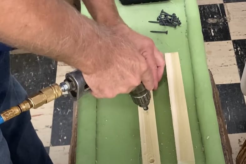 A man is using a drill on a piece of wood