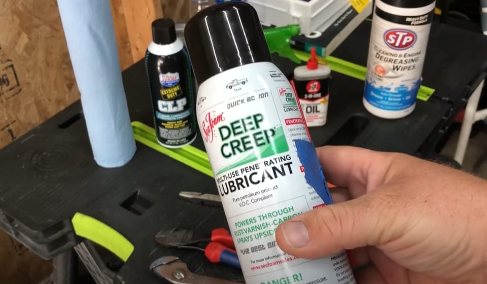 A person holding a deep creep lubricant bottle