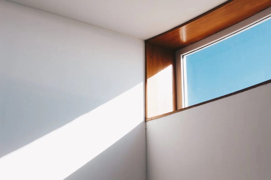 A sun peeking at the top window of a home