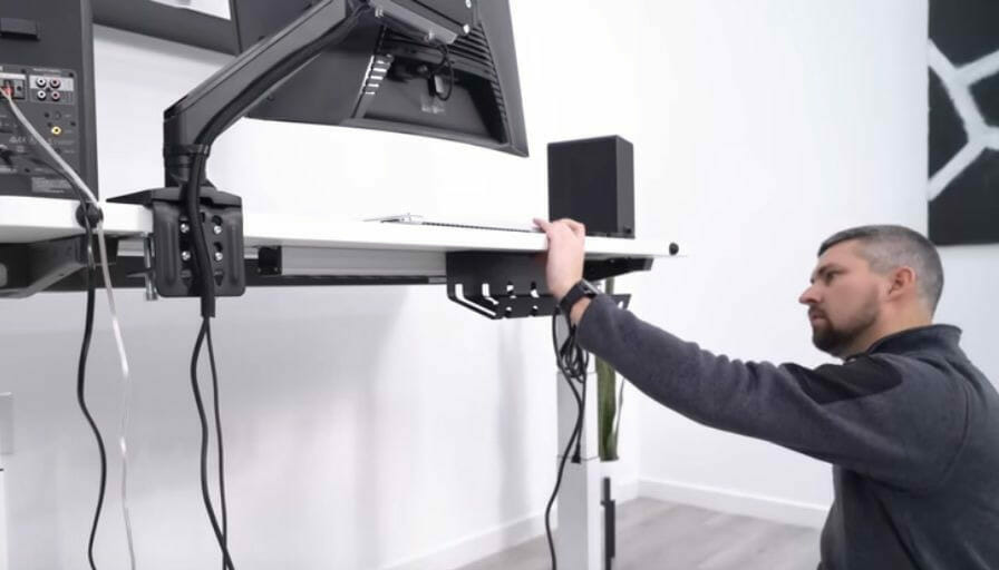 A man installing a monitor mount on a desk