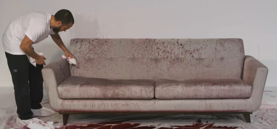 A man dabbing the stained couch with liquid