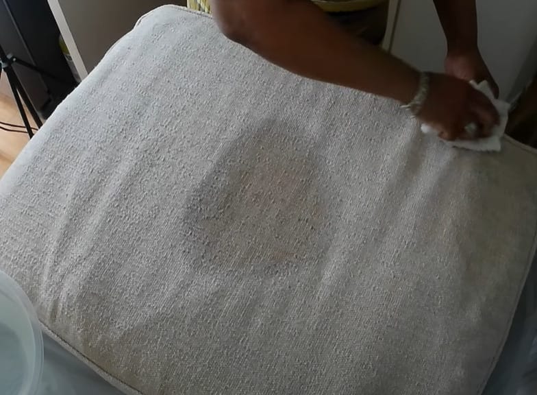 A person cleaning the upholstery furniture