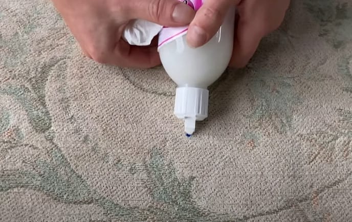 A person pouring an alcohol based solution to an upholstery