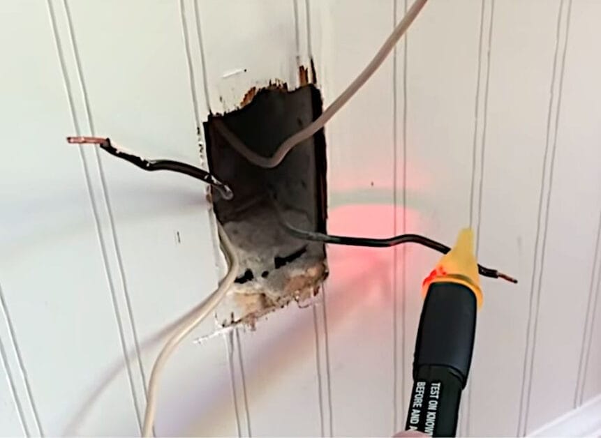 A person is using a voltage tester to check the wire's outlet on the wall