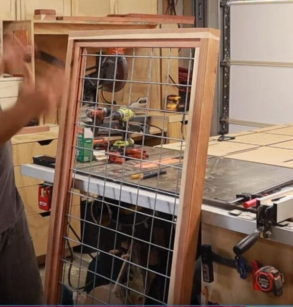 a person making his own panel mesh wire with wood frame