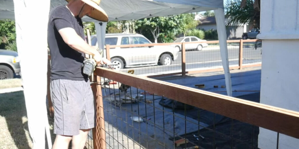 A man stapling the wire mesh to the upper rails