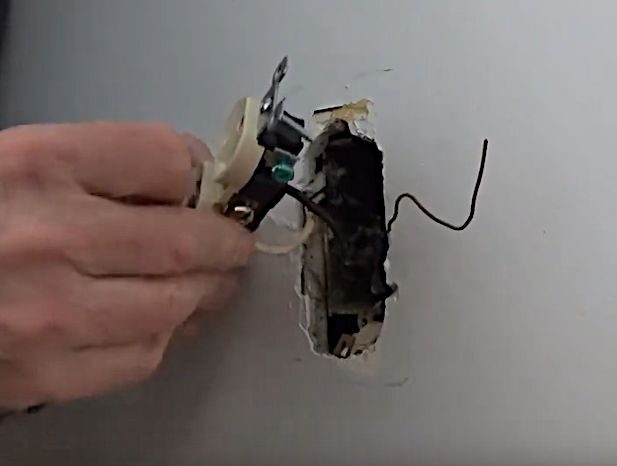 A person is removing an outlet from the wall