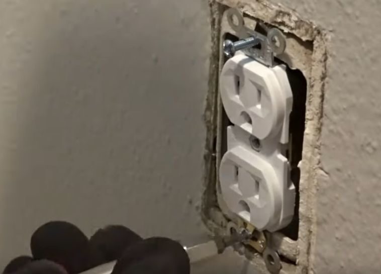 A person attaching a new outlet on the wall