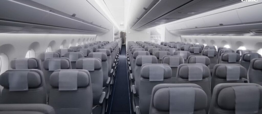 The commercial interior of an airplane with rows of seats featuring different types of upholstery