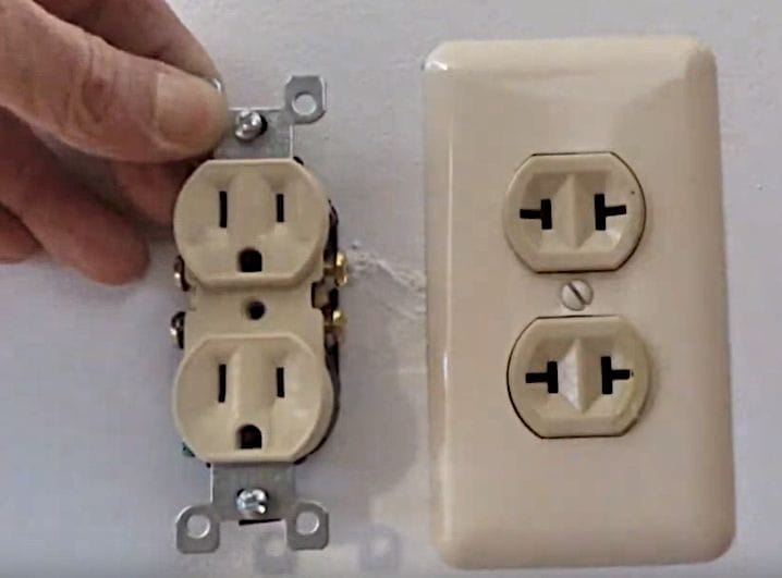 A person holding a new outlet to replace the old one