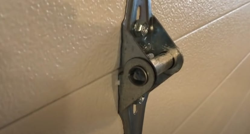 A hinge and roller of a garage door installed at the wall