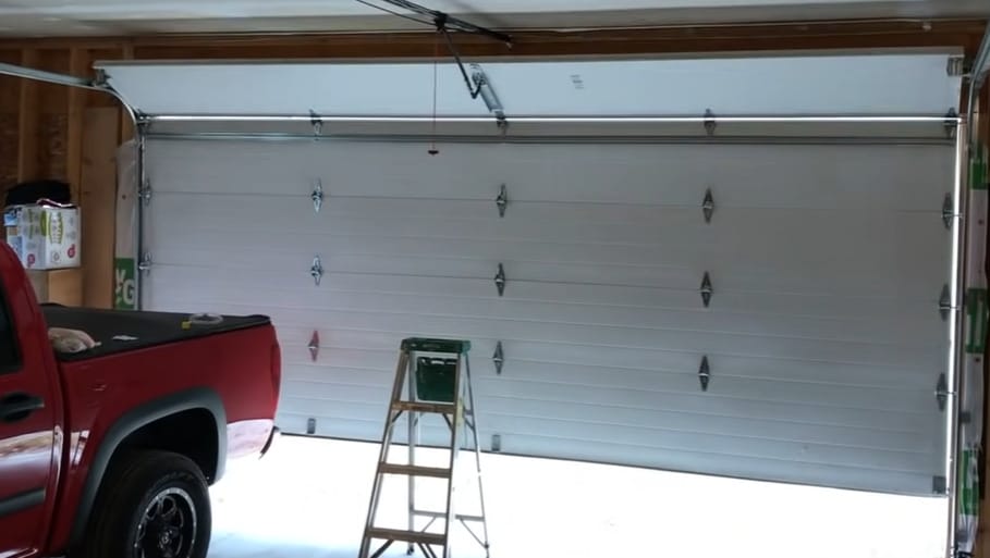 A garage in the inside with half open door and a ladder in front of it