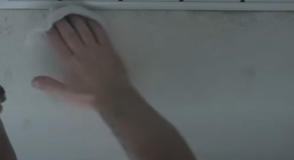 A person wiping the wall with dry towel