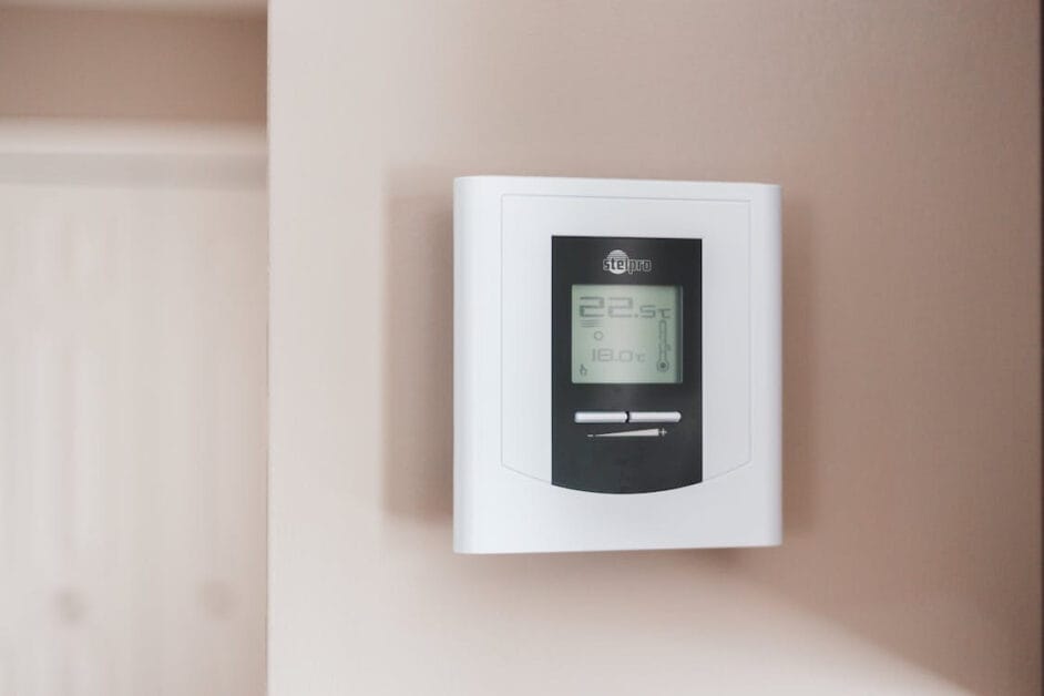 A programmable thermostat installed on the wall of a room