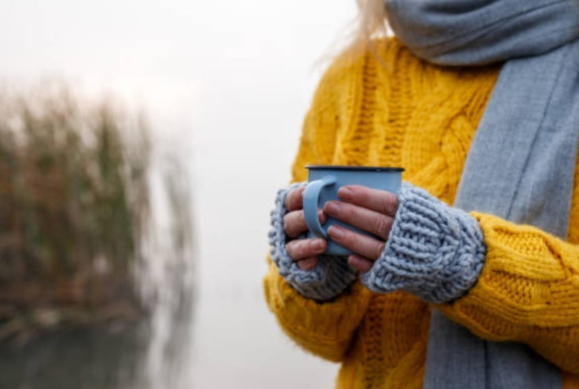 A woman in a yellow sweater enjoying a cup of coffee