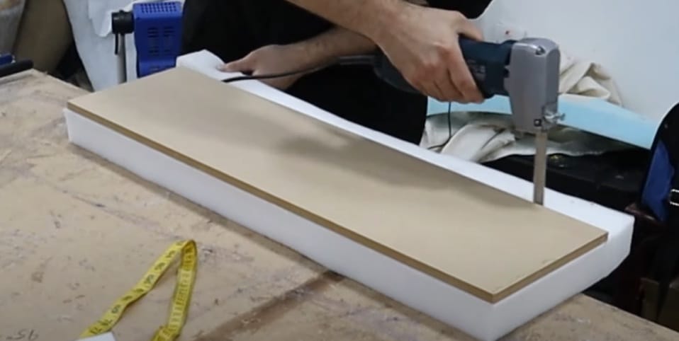 A person cutting the foam on the table using a foam cutter tool