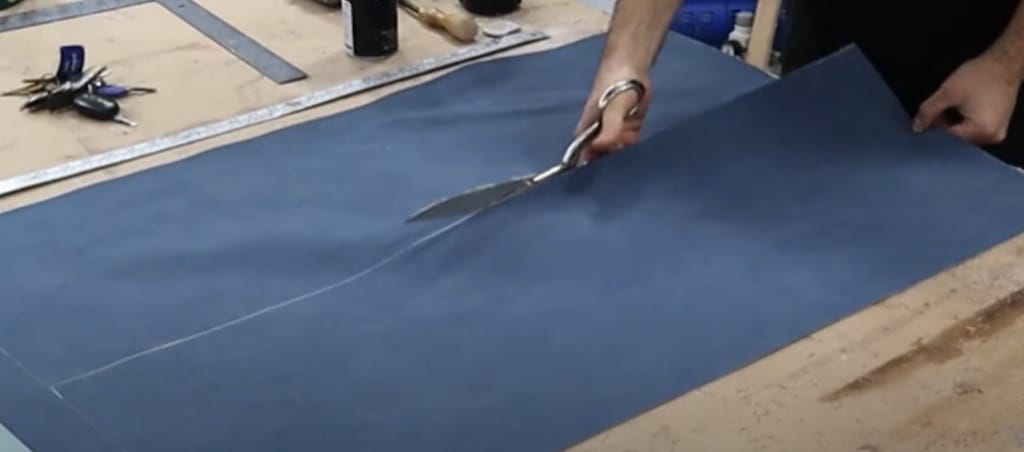 A person cutting with scissors a piece of fabric for upholstery