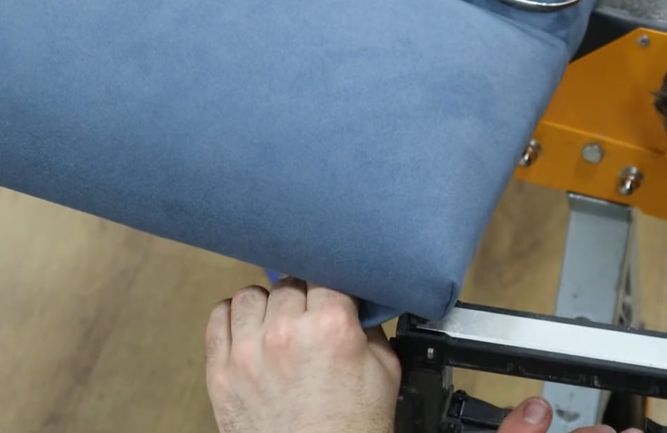 A person tufting securely the fabric to the frame