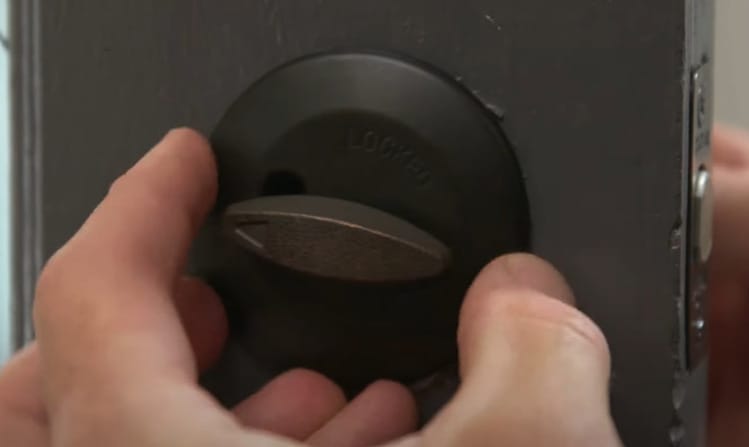 A person using a deadbolt lock on the door