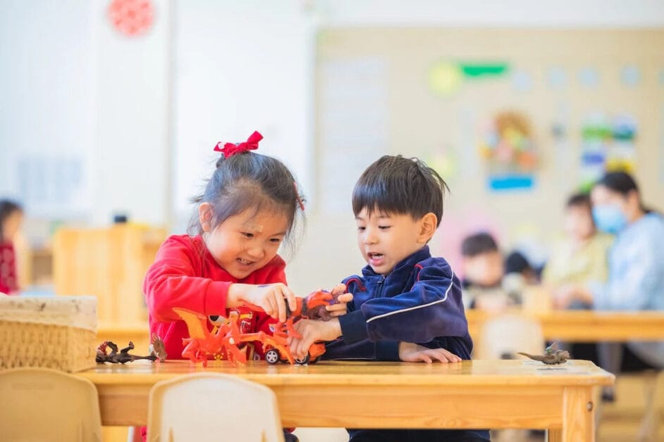 A girl and a boy kid playing at a classroom