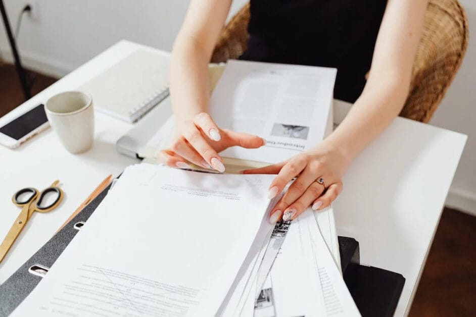 A woman checking a piled document on her desk